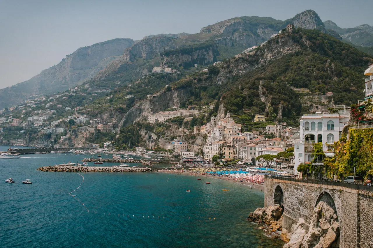 Amalfi town and its harbour beneath steep green mountains on the Amalfi Coast, Italy
