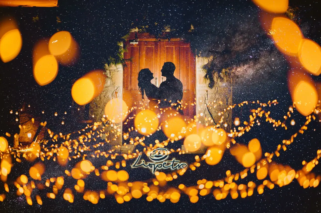 Lucin and Sal silhouetted in a doorway beneath a starry sky and fairy lights at Liopetro, Kouklia