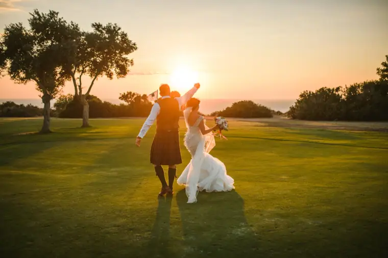 Melissa and Marc dancing across a golf course lawn into the sunset, Aphrodite Hills