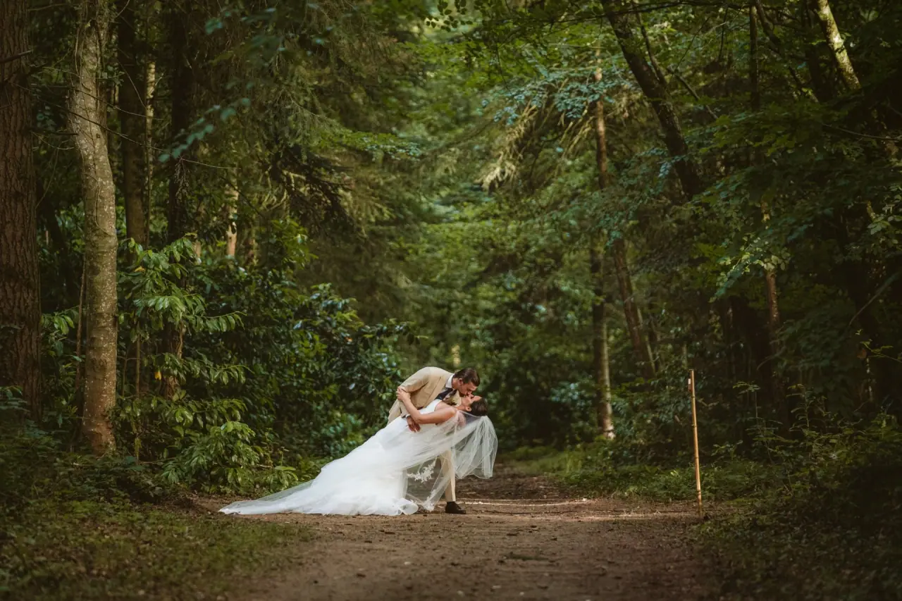 Lauren and Josh sharing a dip kiss on a woodland path at Château de la Basmaignée, France