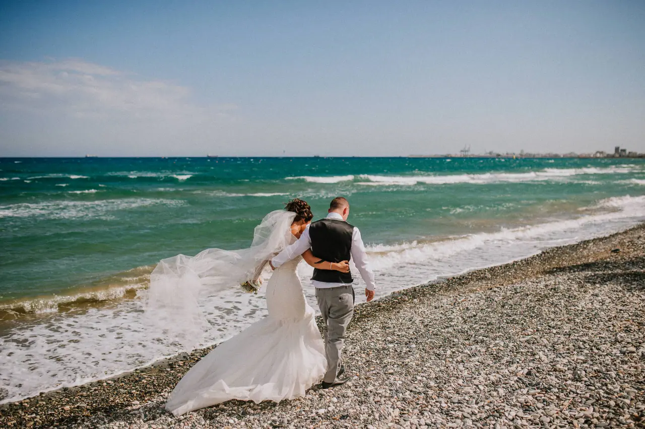 Louise and Mike walking along the shingle beach as waves roll in at Galu Seaside, Larnaca