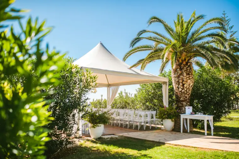 White gazebo among palm trees and lawns set for the ceremony at Nissi Beach Resort