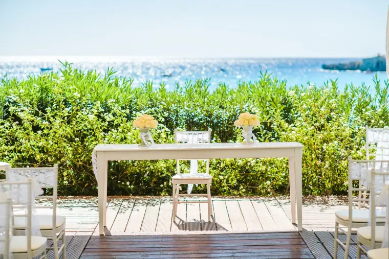 Ceremony table with yellow roses on a wooden deck overlooking the sea, Nissi Beach Resort