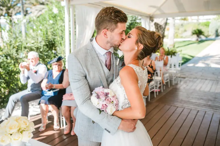 Naomi and Dale's first kiss under the canopy as guests watch, Nissi Beach Resort