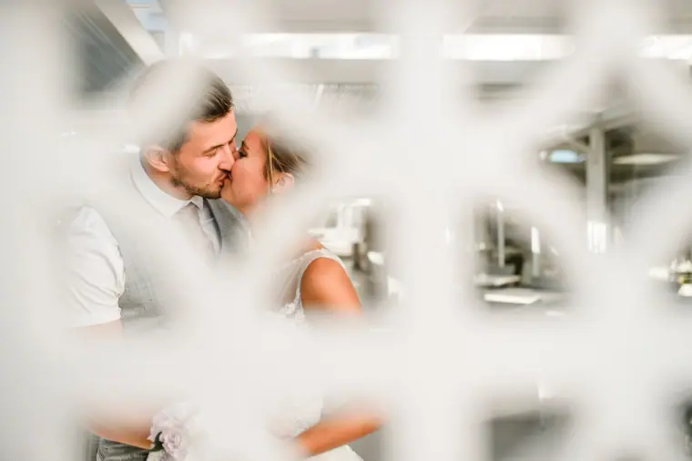 Newlyweds kissing, seen through a white lattice screen