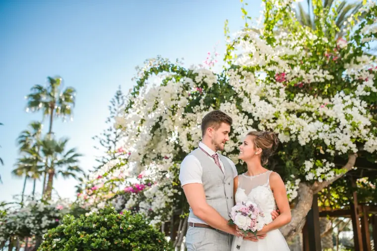 Couple framed by white bougainvillea and palm trees at Nissi Beach Resort