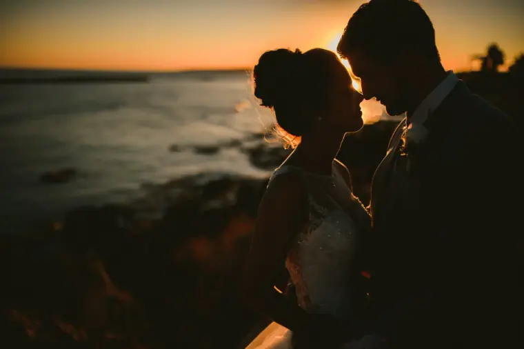 Silhouette of the bride and groom face to face against the evening sea