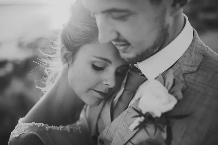 Black-and-white close-up of the bride leaning into her groom's shoulder