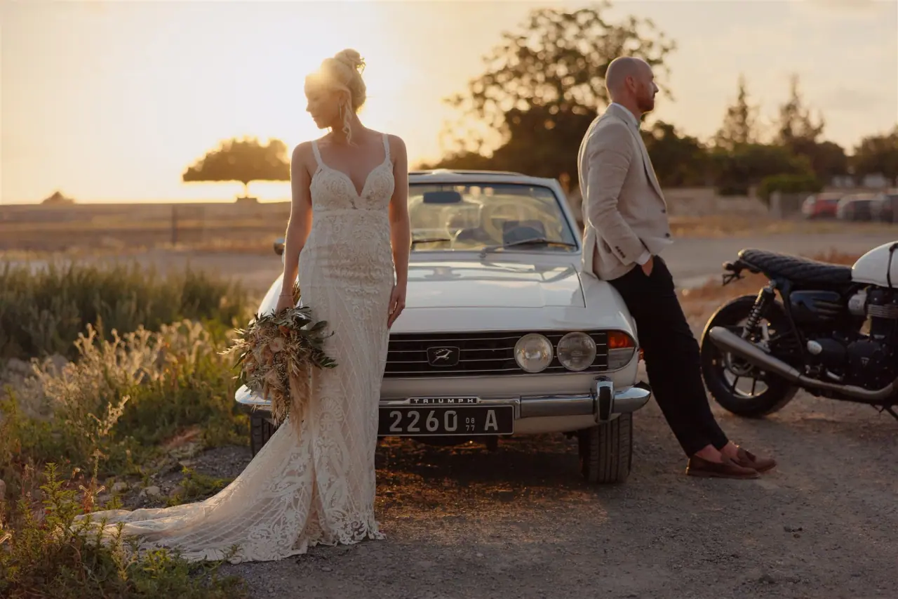 Sarah and Ben at sunset beside a vintage white convertible and a motorbike at Liopetro, Paphos
