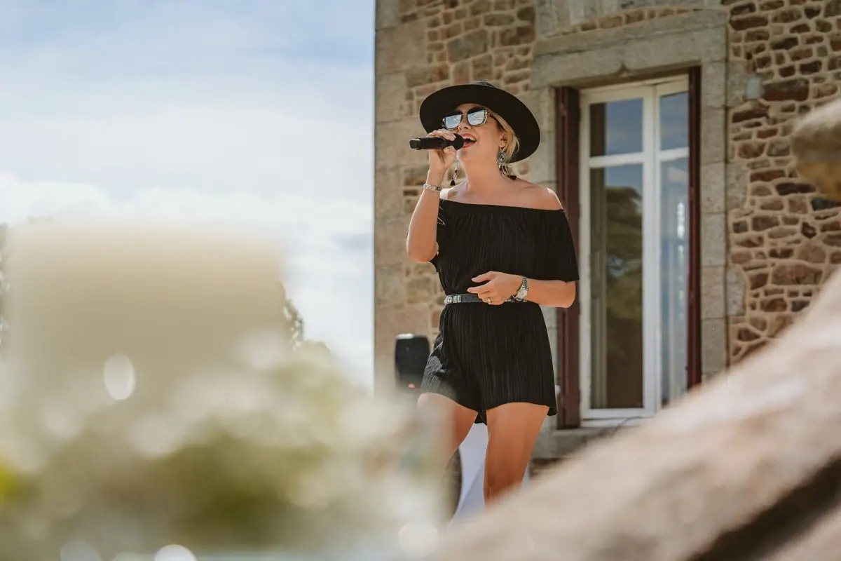 Singer in a black hat and dress performing at Lauren and Josh's wedding, Château de la Basmaignée, France