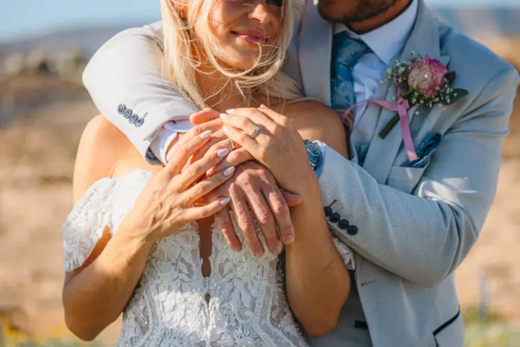 Close-up of Jayley's hands on Nick's arm, showing their wedding rings, at Alassos