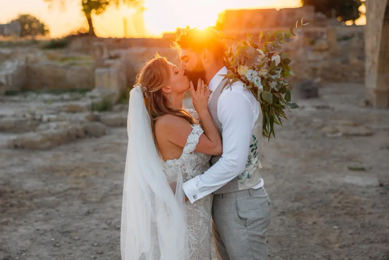 Bride and groom sharing a golden-hour kiss among ancient ruins near Liopetro, Kouklia