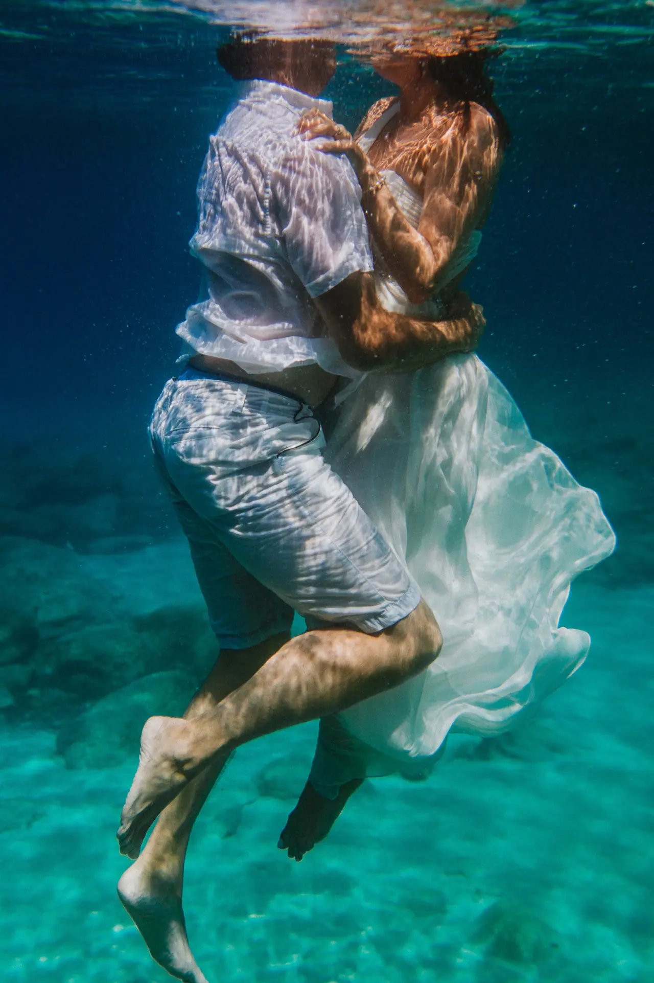 Couple embracing underwater in clear turquoise sea in the Balearic Islands